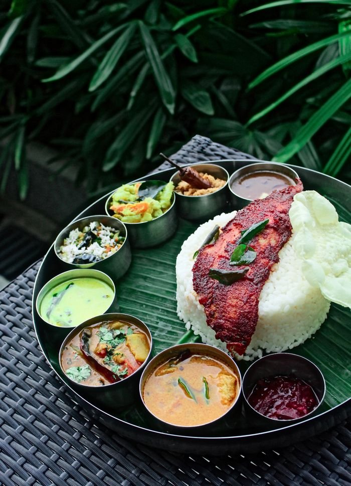 Home Delicious Kerala rice meal with assorted curries and fried fish served on a banana leaf.