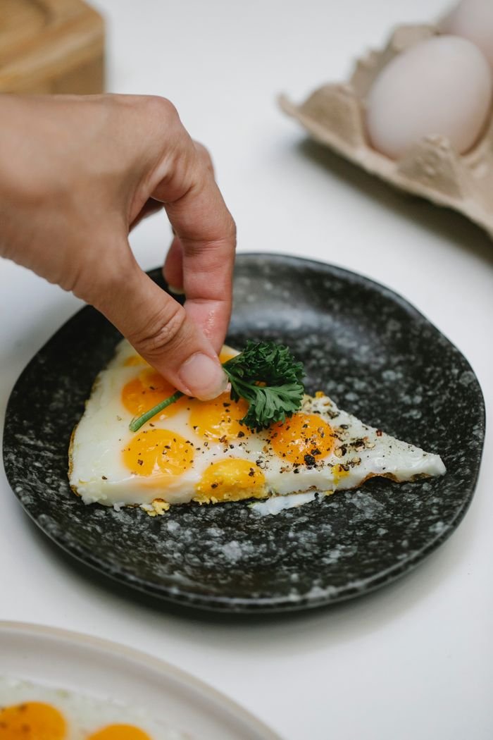 The Art of Drawing Readers In: Your attractive post title goes here From above of crop unrecognizable chef adding sprig of parsley on fried quail eggs placed in plate on table